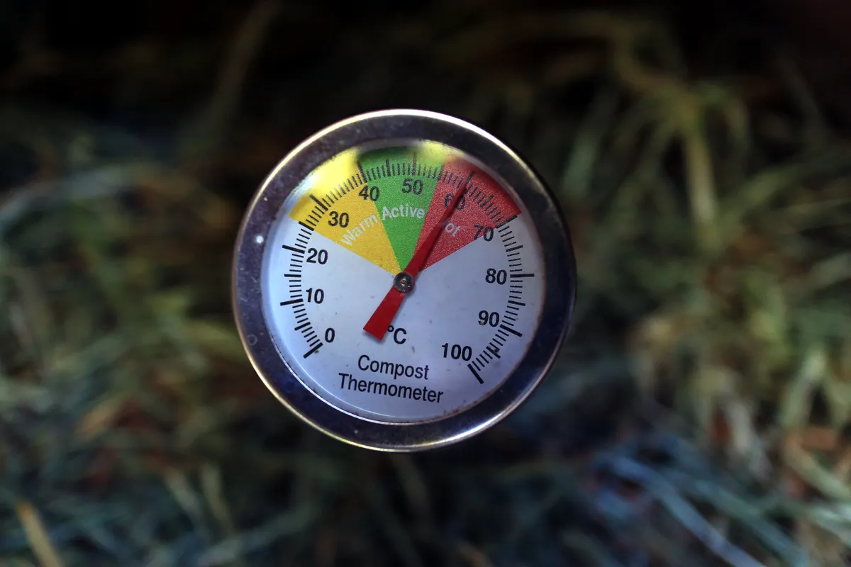Thermomètre à compost planté dans la matière, aiguille dans la zone rouge