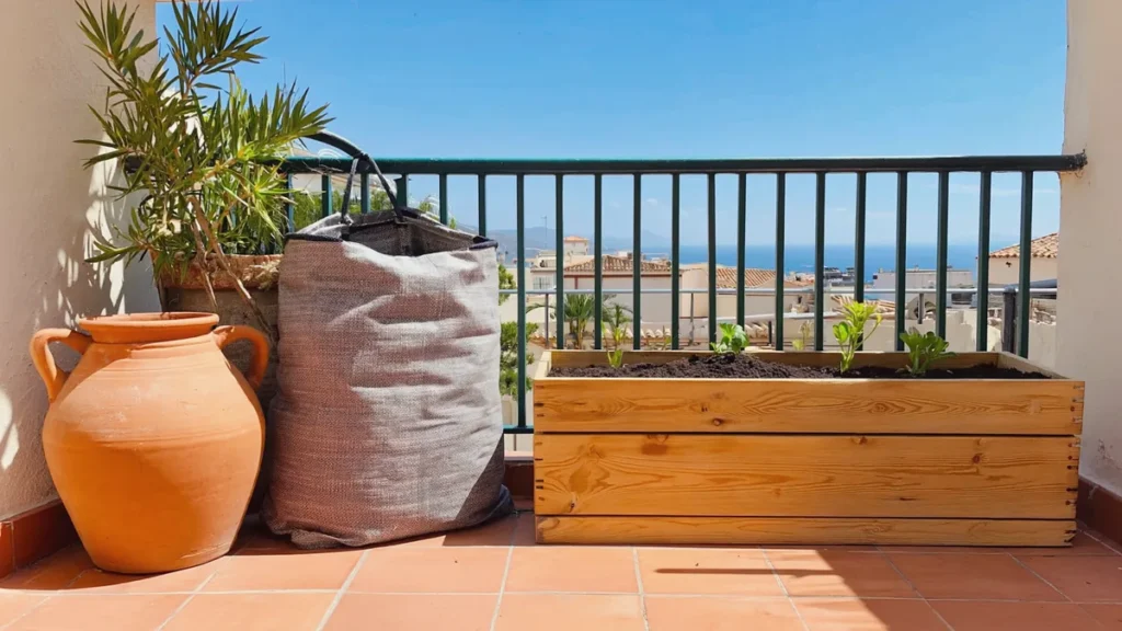 Potager sur balcon en climat méditerranéen: Grand pot en terre cuite, sac de culture en géotextile et bac en bois posés sur un balcon ensoleillé.